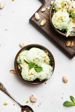 Fıstıklı dondurmalı ezilmiş fındık, nane ile dekore edilmiş yaprakları seramik kaseler, gri arka plan, üstten görünüm