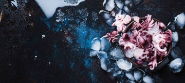 Küçük kırmızı hazır ahtapot ezilmiş buz, ıslak siyah arka plan, üstten görünüm