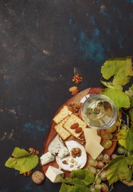 Beyaz SEK şarap, peynir kalıp, fındık, üzüm ve kraker, koyu arka plan, üstten görünüm