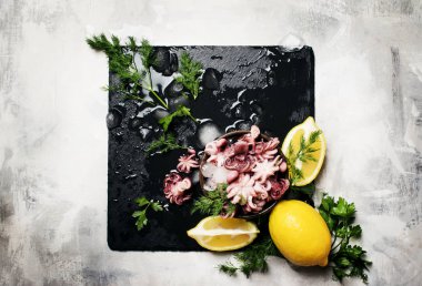 Küçük ahtapot ezilmiş buz, limon ve yeşil otlar, taş arka plan, üstten görünüm ile hazırlanan
