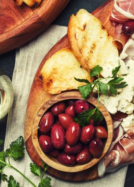 Aperatifler veya antipasti, crostini, prosciutto, mavi peynir ve zeytin, siyah arka plan, görünümü top
