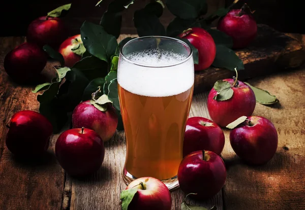 Apple cider in a large beer glass, vintage wooden background, selective focus