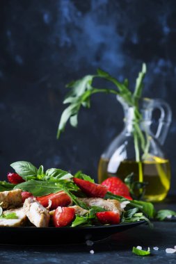 Izgara tavuk salatası, taze çilek ve baharatlı roka, koyu arka plan, seçici odak