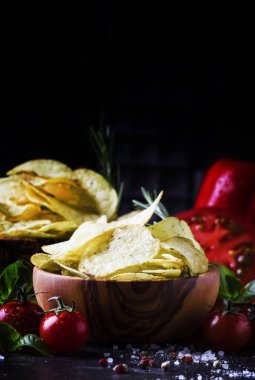 Altın cips sebze, baharat ve fesleğen, seçici odak siyah taş zemin üzerine biberiye ile tuzlu