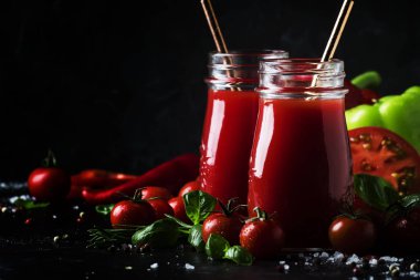 Baharatlı domates suyu biber, biber ve Yeşil fesleğen siyah arka plan, seçici odak üzerine cam şişelerde