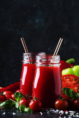 Baharatlı domates suyu biber, biber ve Yeşil fesleğen siyah arka plan, seçici odak üzerine cam şişelerde