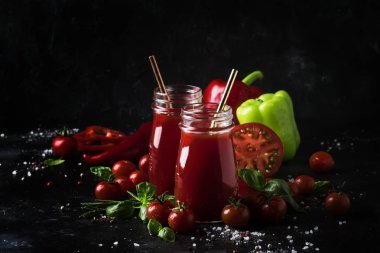 Baharatlı domates suyu biber, biber ve Yeşil fesleğen siyah arka plan, seçici odak üzerine cam şişelerde