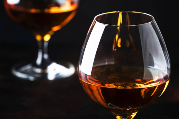Cognac in glasses, dark background, selective focus