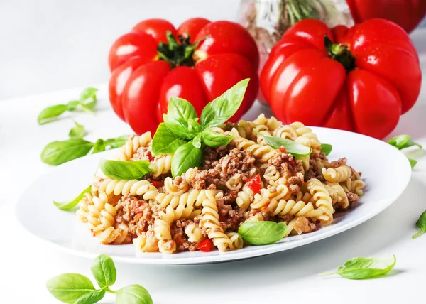 Domates ve fesleğen beyaz plaka, seçici odak üzerinde et sos ile hazırlanmış makarna