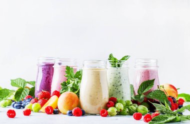 Yoğurt, taze meyve ve çilek gri bir arka planda seçici odak ile sağlıklı ve kullanışlı renkli berry smoothies