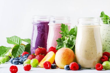 Yoğurt, taze meyve ve çilek gri bir arka planda seçici odak ile sağlıklı ve kullanışlı renkli berry smoothies
