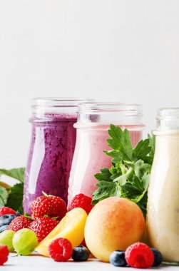 Yoğurt, taze meyve ve çilek gri bir arka planda seçici odak ile sağlıklı ve kullanışlı renkli berry smoothies