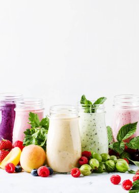 Yoğurt, taze meyve ve çilek gri bir arka planda seçici odak ile sağlıklı ve kullanışlı renkli berry smoothies