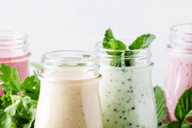 Yoğurt, taze meyve ve çilek gri bir arka planda seçici odak ile sağlıklı ve kullanışlı renkli berry smoothies
