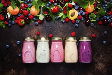 Yoğurt, taze meyve ve kahverengi zemin üzerinde ham meyveleri ile sağlıklı ve kullanışlı renkli berry smoothies görünümü top