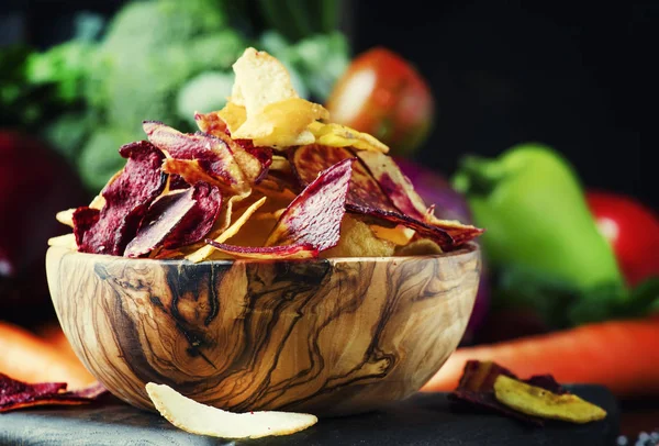 Vegan snacks, multicolored vegetable chips in  wooden bowl
