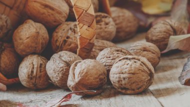 Taze ceviz sızıntısı eski ahşap masa üzerinde düşen yapraklar ile sonbahar arka plan üzerinde bir hasır sepet dışarı