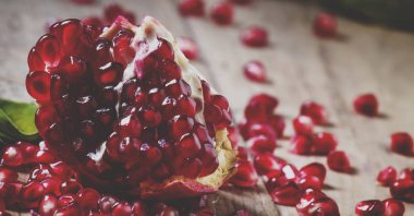 Eski ahşap masa üzerinde yakut kırmızı fasulye taze soyulmuş nar