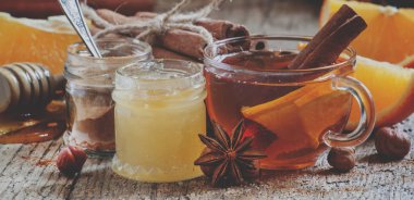 Turuncu, bal ve tarçın eski ahşap masa üzerinde bir cam bardak ile kış çayı