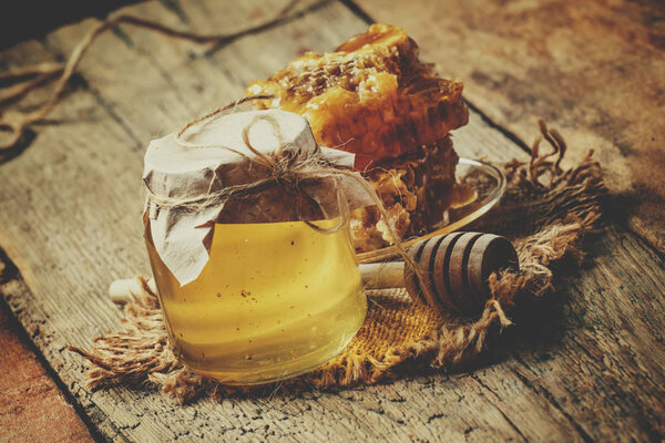 Горный мед в стеклянной банке и сотах, винтажный деревянный фон
