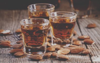 Eski ahşap arka plan üzerinde kuru badem ile İtalyan amaretto likör