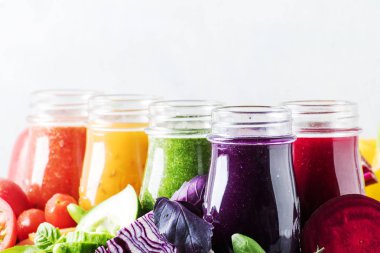 Çok renkli vegan sebze suları ve smoothies gri tablosudur, seçici odak üzerinde cam şişelerde
