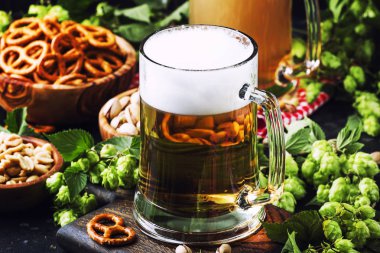 Büyük cam, taze yeşil atlama ve kase tuzlu atıştırmalıklar ve fındık, sonbahar bira festivali kavramı, koyu arka plan, seçici odak ile hafif Alman bira dökülür