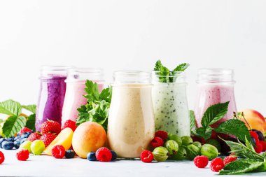 Sağlıklı ve kullanışlı renkli berry cokctalis, smoothies ve yoğurt, taze meyve ve çilek gri tablo, seçici odak milkshakes