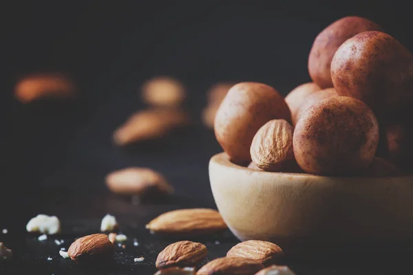 Marzipan, round almond candies in wooden bowl on dark table, selective focus