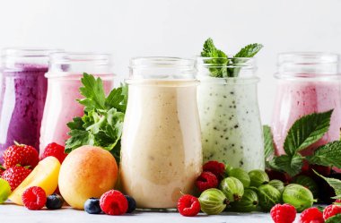 Sağlıklı ve kullanışlı renkli berry cokctalis, smoothies ve yoğurt, taze meyve ve çilek gri tablo, seçici odak milkshakes