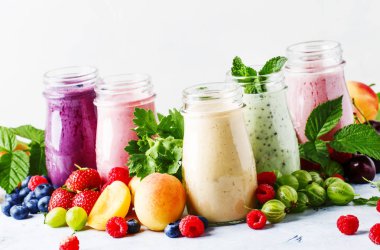 Sağlıklı ve kullanışlı renkli berry cokctalis, smoothies ve yoğurt, taze meyve ve çilek gri tablo, seçici odak milkshakes