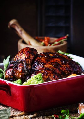 Sır pişmiş tavuk pişirme eski ahşap masa, rustik tarzı, seçici odak için kırmızı formunda sebzeli