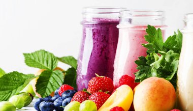 Sağlıklı ve kullanışlı renkli berry cokctalis, smoothies ve yoğurt, taze meyve ve çilek gri tablo, seçici odak milkshakes
