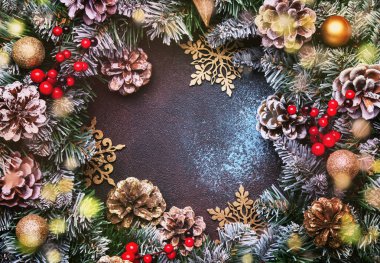 Yeşil kar köknar dalları, çam kozalakları, altın kar tanesi, Noel topları, kırmızı meyveler ve çalar saat kahverengi zemin, üstten görünüm Noel ve yeni yıl çerçeve kompozisyonu