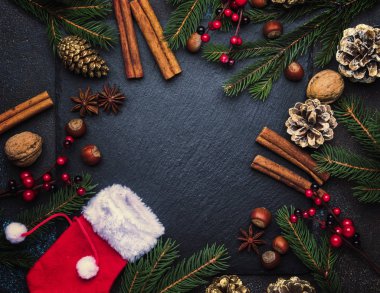 Noel ve yeni yıl koyu arka plan, çerçeve, şablonla Festival süsleri, kış baharat ve Noel süsleri, fındık ve çam dalları, üstten görünüm