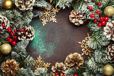 Yeşil kar köknar dalları, çam kozalakları, altın kar tanesi, Noel topları, kırmızı meyveler ve çalar saat kahverengi zemin, üstten görünüm Noel ve yeni yıl çerçeve kompozisyonu