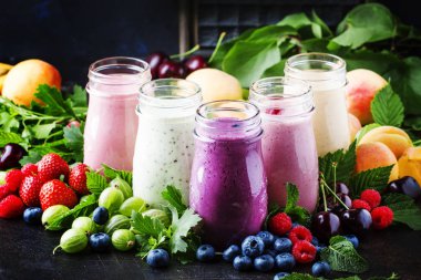 Sağlıklı ve kullanışlı renkli berry kokteyller, smoothies ve yoğurt, taze meyve ve çilek kahverengi tablo, seçici odak milkshakes