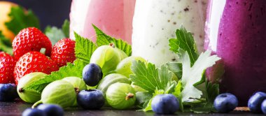 Sağlıklı ve kullanışlı renkli berry kokteyller, smoothies ve yoğurt, taze meyve ve çilek kahverengi tablo, seçici odak milkshakes