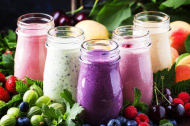 Sağlıklı ve kullanışlı renkli berry cokctalis, smoothies ve yoğurt, taze meyve ve çilek kahverengi tablo, seçici odak milkshakes