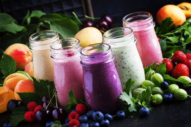 Sağlıklı ve kullanışlı renkli berry cokctalis, smoothies ve yoğurt, taze meyve ve çilek kahverengi tablo, seçici odak milkshakes