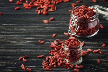 Goji meyveleri cam kavanoz, koyu ahşap masa, seçici odak