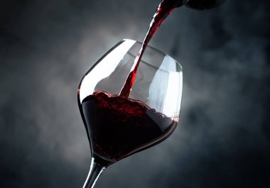 Fransız kuru kırmızı şarap, cam, gri arka plan, seçici odak dökülen