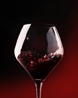 Kırmızı şarap, bir bardak sıçrama kuru cabernet sauvignon, koyu kırmızı arka plan, hareketli resim, sığ derinlik-in tarla defocused