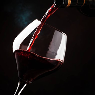 Büyük bardak şarap, şarap tadımı, koyu arka plan, düşük anahtar, seçici odak içine üzümlerinden pinot noir çeşit kırmızı şarap döktü