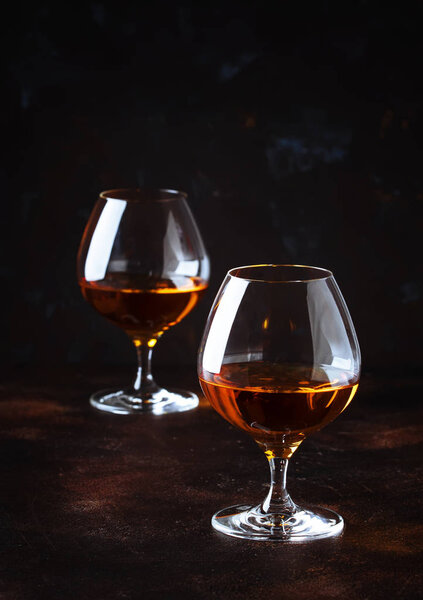 Grape brandy in shot glasses, dark brown background, selective focus