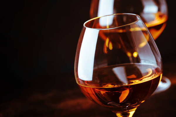Grape brandy in shot glasses, dark brown background, selective focus