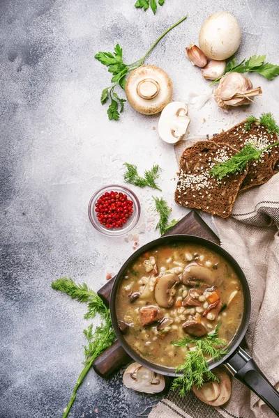 Hot thick mushroom soup with beef, spices and wholegrain barley, meat broth. With black bread, in metal pan, top view, flat lay, gray kitchen table backgound — Stock Image Hot Thick Mushroom Soup Beef Spices Wholegrain Barley Meat Broth Royalty Free Stock Photos