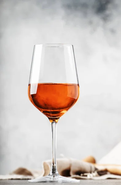 Trendy food and drink, orange wine in glass, gray table background, space for text, selective focus vertical image