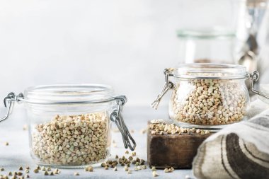 Cam kavanoz, sağlıklı vejetaryen yiyecekler veya çiğ gıdalar kavramı, gri mutfak masa artalanını, seçici odak yeşil buğday