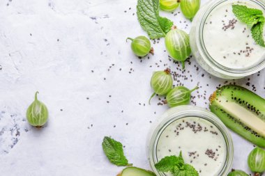 Bektaşi üzümünden meyve suyu ve milkshake, kivi ve yoğurtlu süt kokteyli? Chia tohumları, gri mutfak masası arka planı, düz yatak, üst görünüm